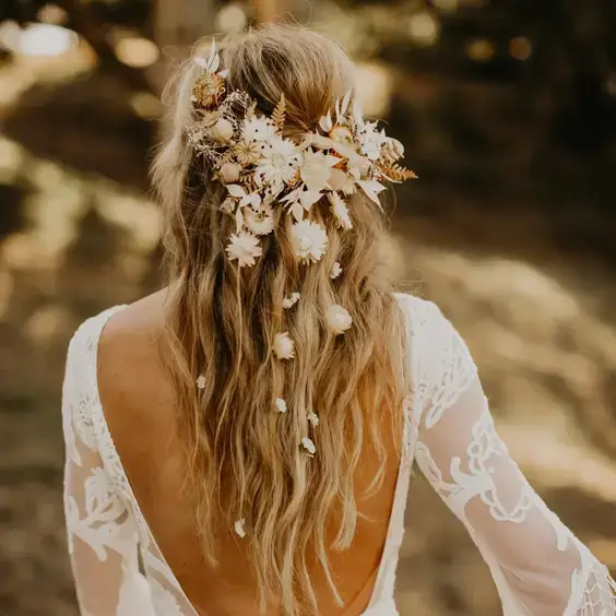 Boho svadobný účes s rozpustenými vlasmi zdobenými kvetmi, ideálny pre prírodný a romantický vzhľad.